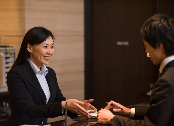 Hospitality front desk employee welcoming a guest.